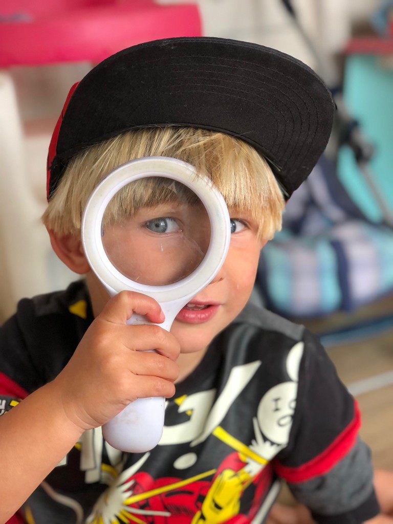 small child playing with large magnifying glass