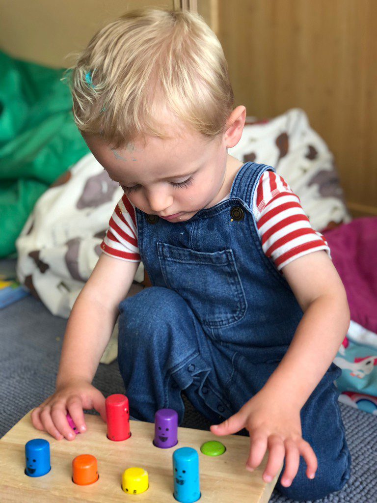 child playing with coloured pegs