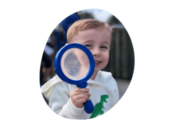 toddler playing with giant magnifying glass