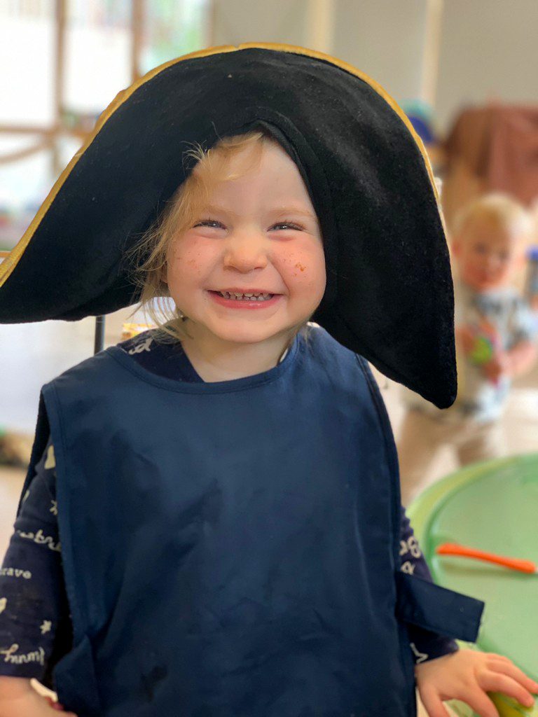 child dressing up in big black hat